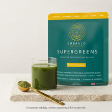Emerald Nutrition SuperGreens package with a glass of green juice on a white background